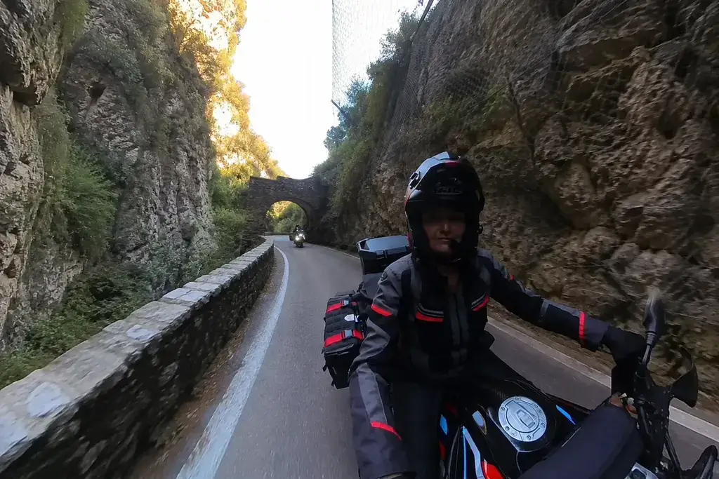 Motociclista lungo la Strada della Forra tra le pareti rocciose di Tremosine.